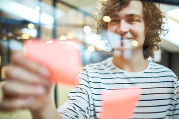 Young employee taking reminder from notice board while working in office