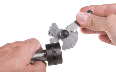 Thread pitch gauge measurement close-up. Detail of the machinist's hands with the set of threaded...