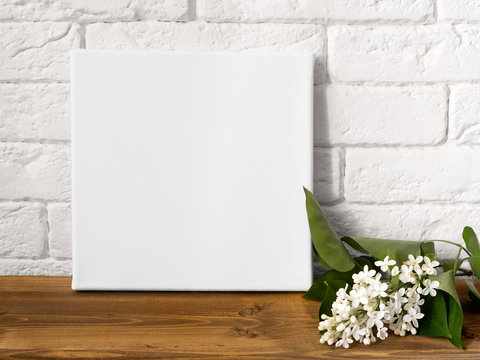 Mock up poster frame and flowers. White square canvas against a brick wall.