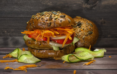 Vegetable vegetarian Burger on a wooden table, healthy food. A delicious lunch for those who lose weight. Burger with carrots and cucumber.