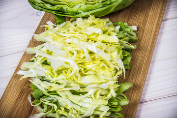 Raw young cabbage on a white wooden background.