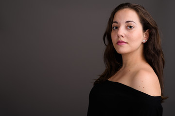 Naklejka premium Young beautiful woman wearing black off-shoulder top against gra