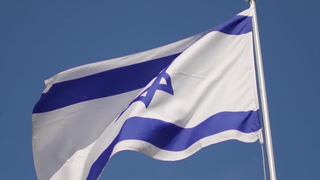 Israeli flag is developing against the blue sky