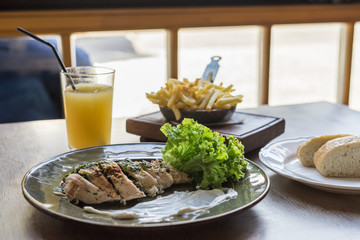 Meat with sauce and salad on wooden table. Glass of fresh juice.