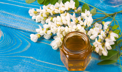 Acacia honey in a glass jar on a blue wooden background.
