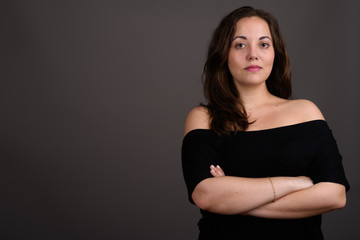 Young beautiful woman wearing black off-shoulder top against gra