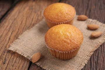 Close up a cup of almond cake against sack fabric on wooden table
