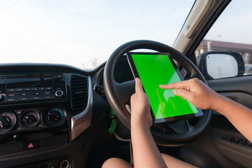Hand of woman using tablet with blank green screen monitor in SUV car