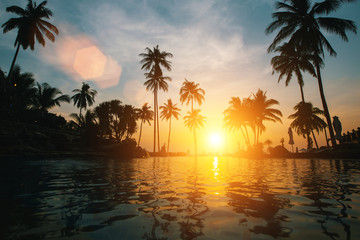 Amazing sunset on tropical beach with silhouettes of palm trees..