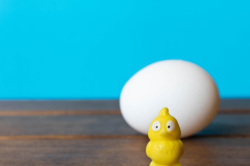 A big white chicken egg with a little yellow toy chicken .