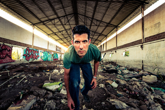 hombre joven serio  en granja abandonada