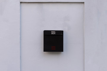 Black mailbox at house wall.