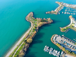 Fototapeta premium Aerial view of sailing yachts and boats near wooden piers. Top view of American city large boat parking near sea coast. Island and parks with green grass. Beginning of summer concept.