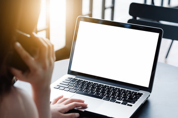 Mockup image of a businesswoman using laptop with blank white desktop screen with coffee cup on wooden table in cafe