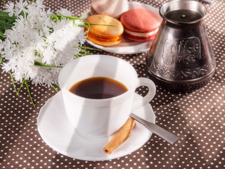 Cup of coffee, cakes on the table and white flowers