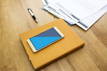 Working table with notepad, pen, document and smartphone. Wooden table background. Office background.