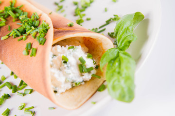 Pancake with cottage cheese and chives decorated with basil