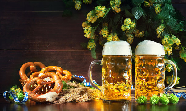 Bavarian beer with soft pretzels, wheat and hop on rustic wooden table