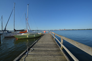 Fototapeta na wymiar Bootssteg -Blick nach Stralsund, Hafen Altefähr, Rügen