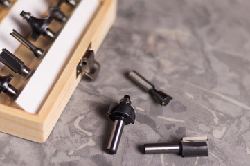 Set of steel router bit for milling cutter in rectangle wooden box with metal lock near three bits...
