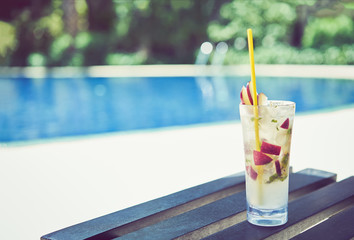 A glass of water juice on swimming pool in vacation and summer time.