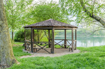 A wooden gazebo with a tiled roof on the bank of the Adda river in Calolziocorte