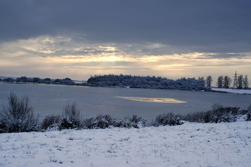 frozen lake in winter at sunset
