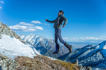 Tourist hikers in the high jump in the background of snowy mountains. Concept of adventure, freedom...