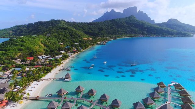 Aerial view of tropical paradise of Bora Bora island, turquoise crystal clear water of scenic blue lagoon, typical over water bungalows, Matira Point - South Pacific Ocean, French Polynesia from above