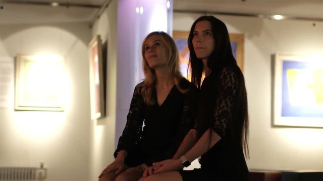 girlfriends discuss paintings in the museum's art gallery