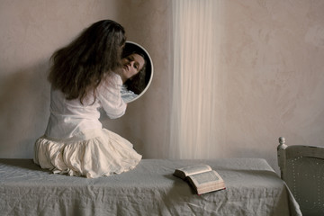 woman reading a book and looking herself through mirror