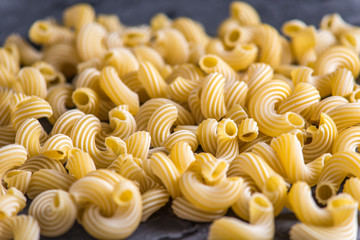 Uncooked italian pasta in the form of spirals on a dark background. Concept of composition of food design.