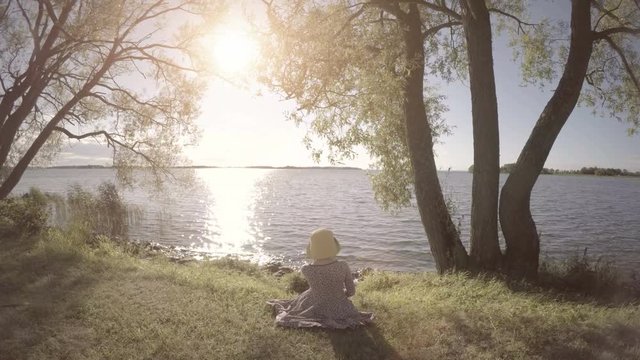 Little girl looking at lake. Calm and beautiful nature scene. Peaceful and idyllic summer landscape.