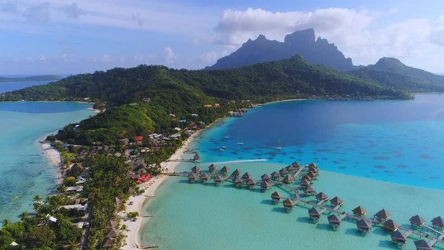 Aerial view of tropical paradise of Bora Bora island, turquoise crystal clear water of scenic blue lagoon, typical over water bungalows, Matira Point - South Pacific Ocean, French Polynesia from above