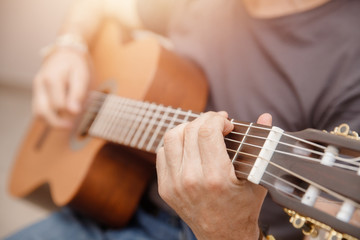 Man plays an acoustic wooden guitar, clamps chords, large plan