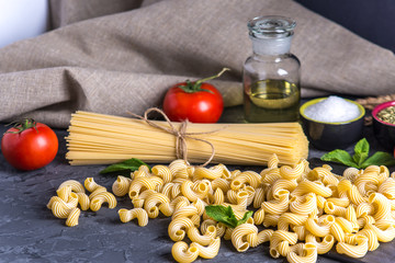 Uncooked pasta cavatappi and spaghetti with ingredients for tomato sauce. Concept of the composition of food design.
