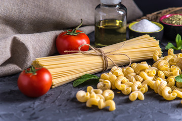 Uncooked pasta cavatappi and spaghetti with ingredients for tomato sauce. Concept of the composition of food design.