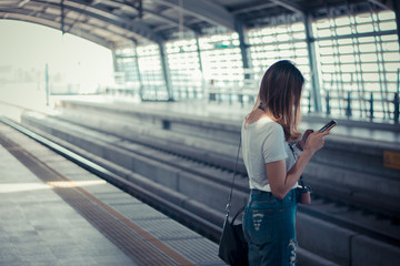 Fototapeta premium Woman waiting on the station platform and using smart phone at the airport link station.