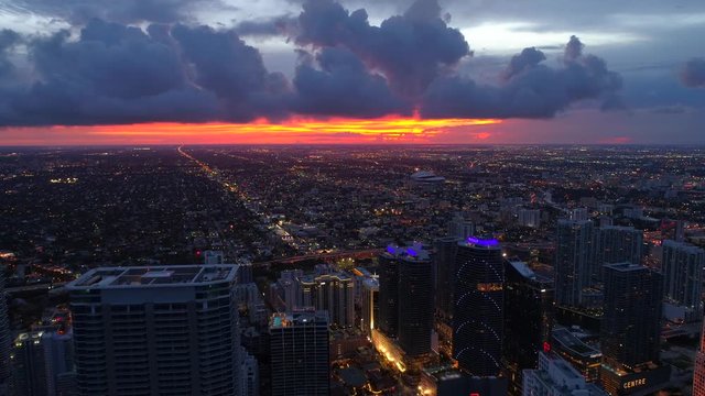 Aerial pull out shot city illuminated at sunset