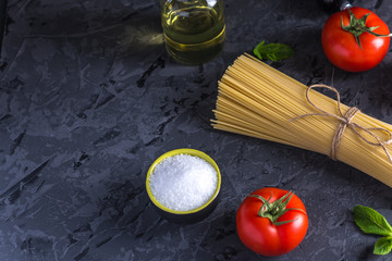 Uncooked pasta spaghetti with ingredients for tomato sauce. Concept of the composition of food design.