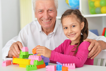 Cute girl and grandfather playing
