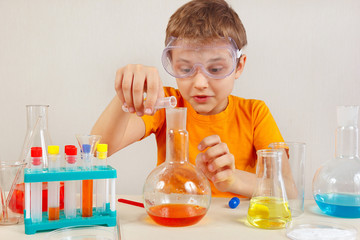Little smart scientist in safety glasses doing chemical experiments in the laboratory