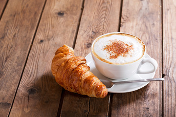 Cup of cappuccino coffee with croissant