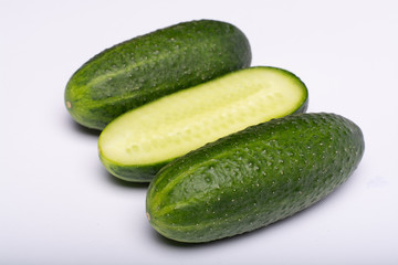 Fresh small green cucumbers whole and sliced close up copy space isolated on white background