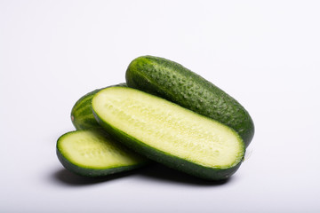 Fresh small green cucumbers whole and sliced close up copy space isolated on white background