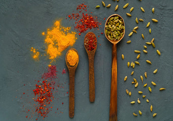 Wooden spoons with spices on a dark background. The concept of vegetarian food,  healthy diet, choice of clean food,  copy  space, closeup.