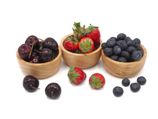 Fresh summer fruits, Cherry, strawberry, and blueberry in wooden bowl isolated on white background.
