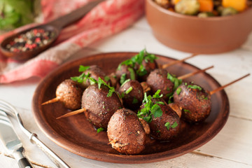 Grilled vegetable skewers with mushrooms and fresh herbs on ceramic plate
