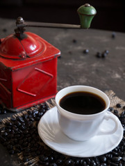 coffee cup with vintage red coffee grinder and beans