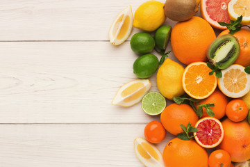 Platter of assorted citrus fruits on white wooden planks, top view